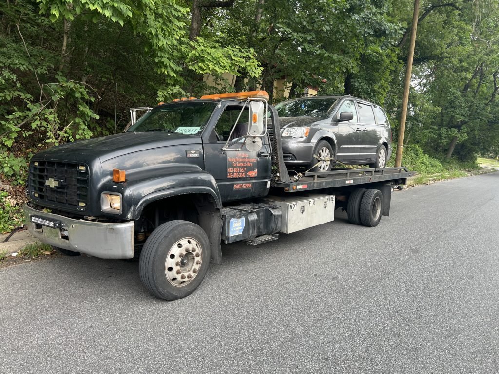 I Got Whipz Towing & Roadside Assistance with a grey chrysler town & country van towing near me from 6400 Windsor Mill Rd, Gwynn Oak, MD 21207 to 700 E 34th St, Baltimore, MD 21218